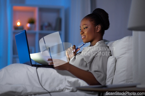 Image of woman with laptop working in bed at night