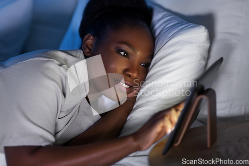 Image of woman with tablet pc in bed at home at night