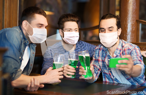 Image of friends with green beer taking selfieat pub