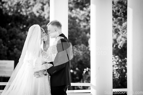 Image of Mixed-racial newlyweds on a walk hugging and looking lovingly at each other, black and white photography