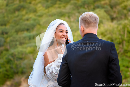 Image of Black bride talking on the phone and looking happily at her white husband
