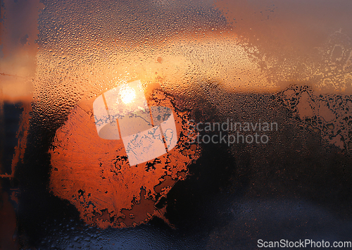 Image of Ice patterns, water drops and sunlight on a winter window glasss