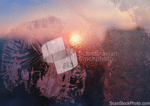 Image of Ice patterns, water drops and sunlight on a window glass 