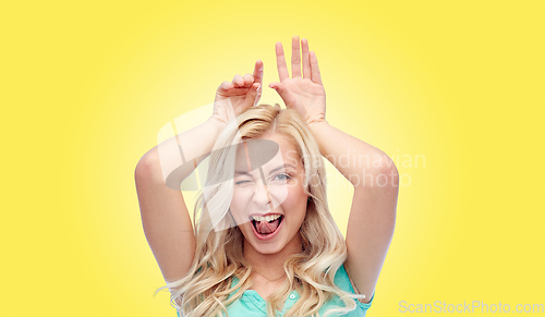 Image of happy smiling young woman making bunny ears