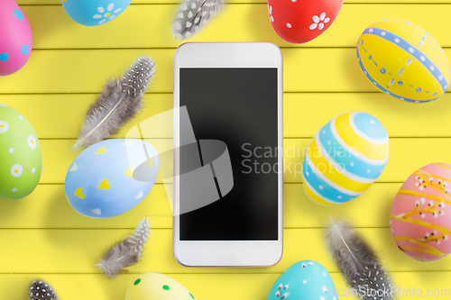 Image of smartphone with easter eggs and feathers on table