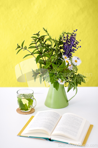 Image of herbal tea, book and flowers in jug on table