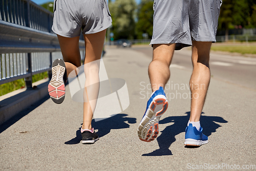 Image of feet of sporty couple running along city road