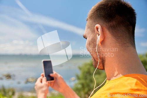 Image of young man with smartphone and earphones outdoors