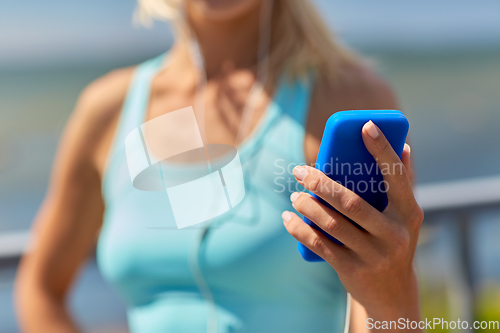 Image of sporty young woman with smartphone and earphones