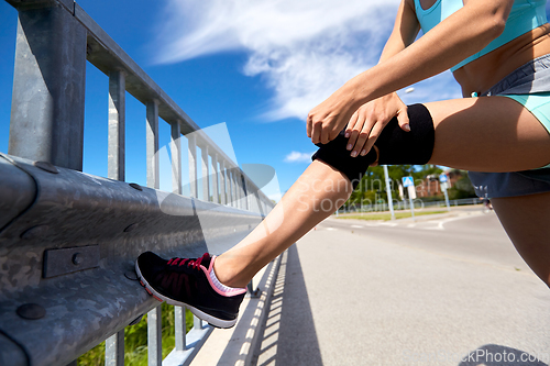 Image of young woman in knee band doing sports outdoors