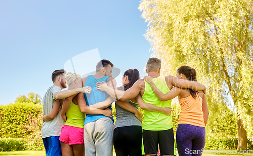 Image of group of happy sporty friends hugging outdoors