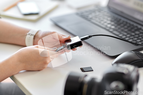 Image of woman with sd card reader and laptop at office