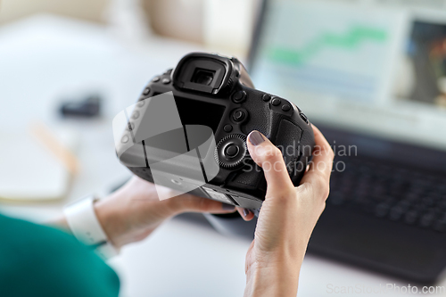 Image of woman with camera and video editor on laptop