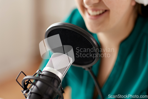 Image of woman with microphone recording podcast at studio