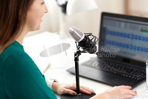 Image of woman with microphone recording podcast at studio