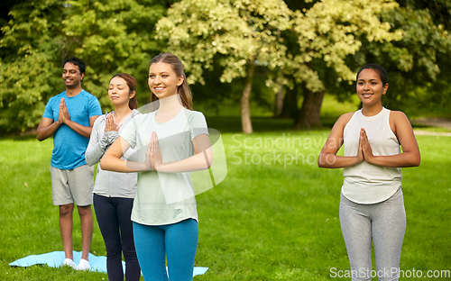 Image of group of people doing yoga at summer park