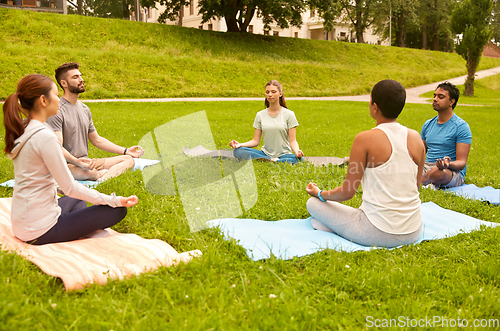 Image of group of people doing yoga at summer park