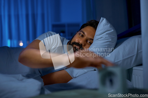 Image of indian man awaking because of alarm clock at night