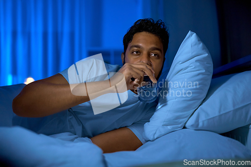 Image of indian man drinking water in bed at night