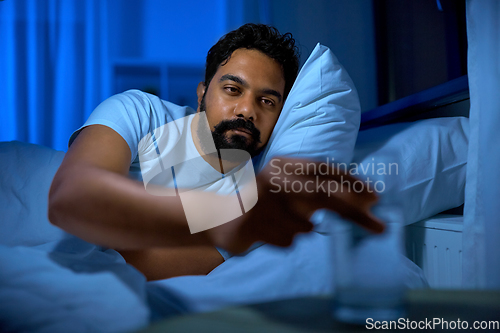 Image of indian man drinking water in bed at night