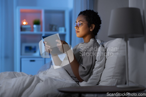 Image of woman with tablet pc in bed at home at night