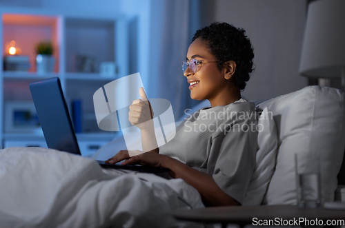Image of woman having video call on laptop in bed at night