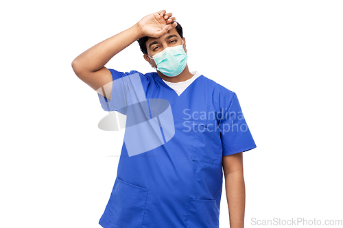 Image of tired indian male doctor in blue uniform and mask