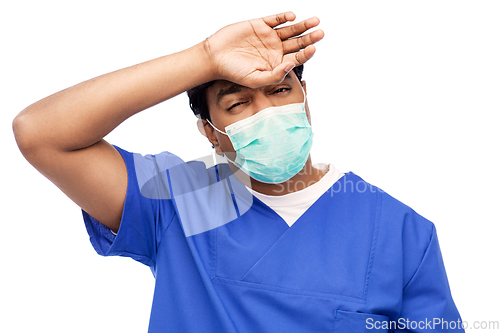 Image of tired indian male doctor in blue uniform and mask