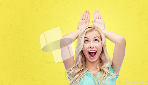 Image of happy smiling young woman making bunny ears