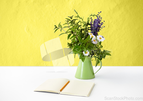 Image of notebook with pencil and bunch of flowers in jug