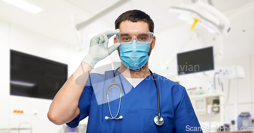 Image of male doctor in goggles, mask and gloves