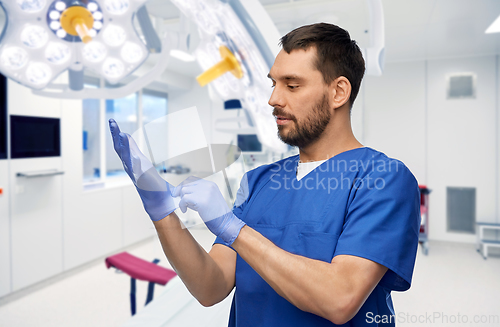 Image of doctor or male nurse putting medical gloves on