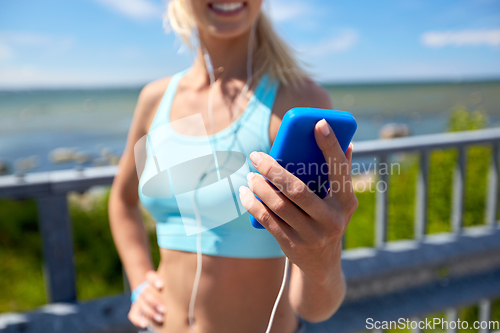 Image of sporty young woman with smartphone and earphones