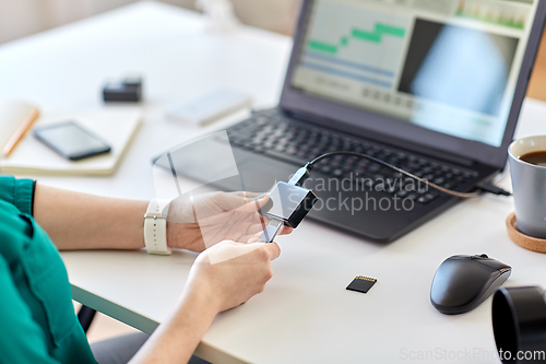 Image of woman with sd card reader and laptop at office