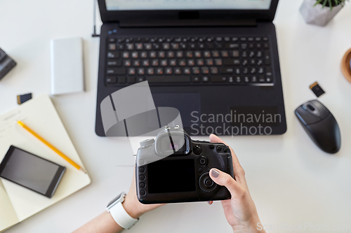 Image of woman with camera and on laptop at office