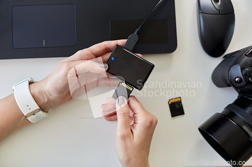 Image of hands with sd card reader, laptop and camera