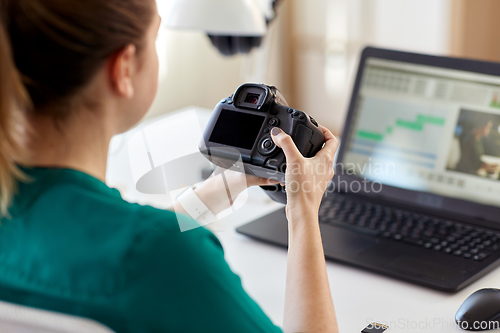 Image of woman with camera and video editor on laptop