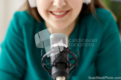 Image of woman with microphone recording podcast at studio