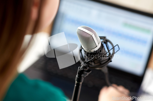 Image of woman with microphone recording podcast at studio