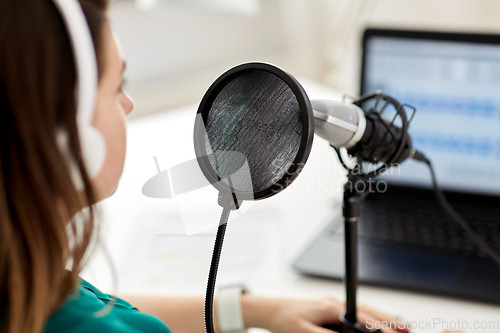 Image of woman with microphone recording podcast at studio