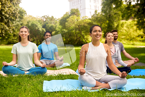 Image of group of people doing yoga at summer park