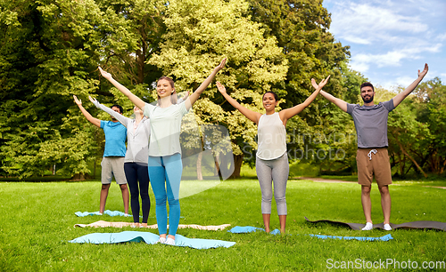 Image of group of people doing yoga at summer park