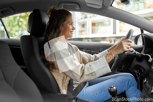 Image of smiling woman or female driver driving car in city