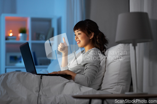 Image of woman having video call on laptop in bed at night