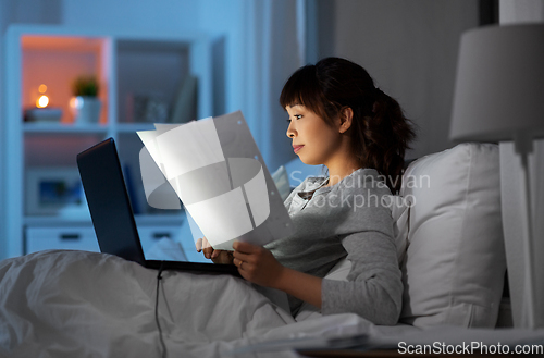 Image of woman with laptop working in bed at night