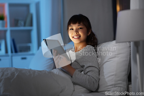 Image of asian woman with tablet pc in bed at home at night