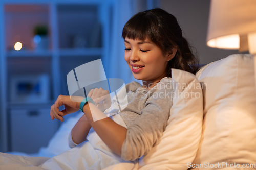 Image of asian woman with health tracker in bed at night