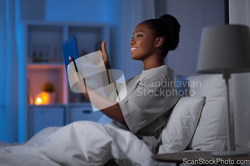 Image of woman with tablet pc having video call in bed