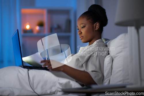 Image of woman with laptop working in bed at night