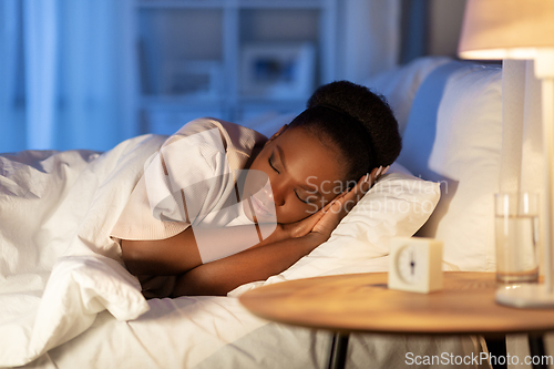 Image of african woman sleeping in bed at home at night